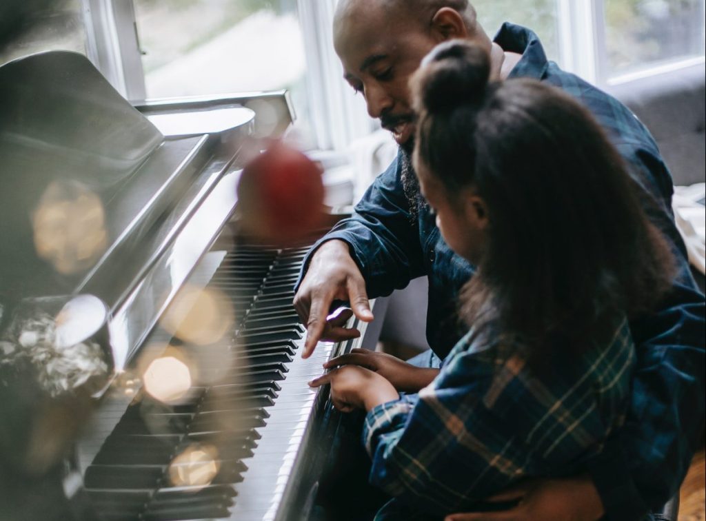 father and daughter playing a keyboard
