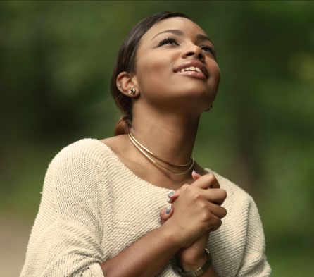 young lady holding her hands together on her chest to pray